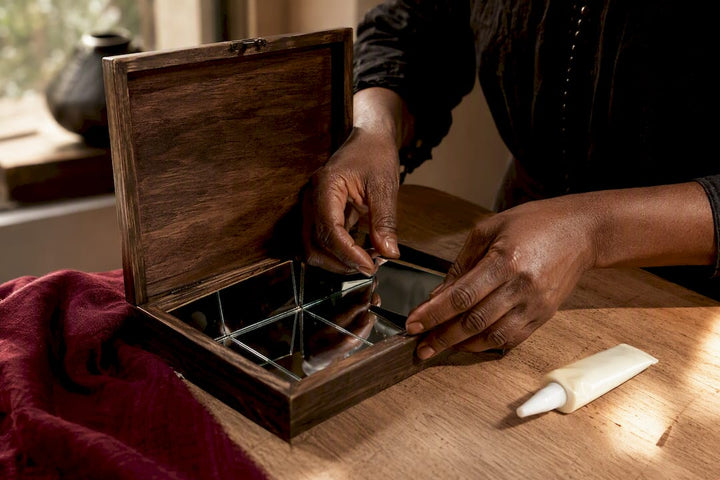 Hands arranging mirrors inside wooden spell box