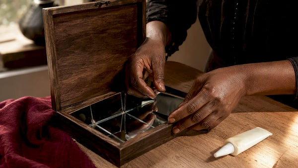 Hands arranging mirrors inside wooden spell box